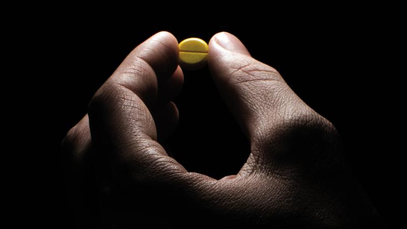 stock getty hand holding a pill dramatic lighting